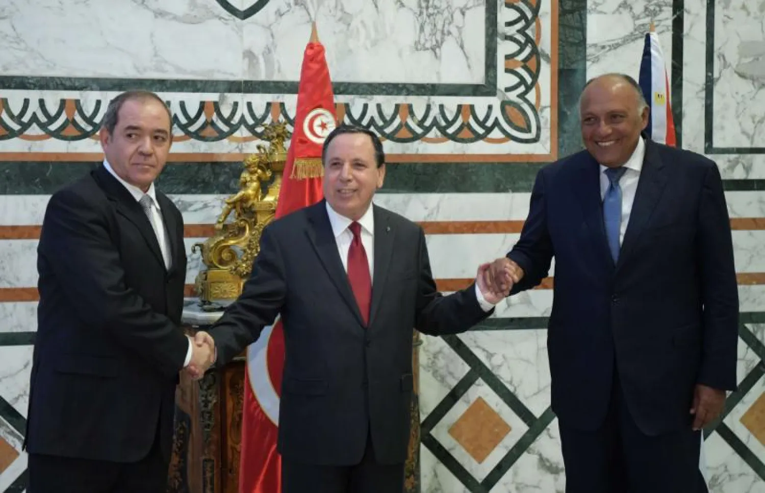 Tunisian Foreign Minister Khemaies Jhinaoui (C) shakes hands with his Egyptian counterpart Sameh Shoukry (R) and Algerian Sabri Boukadoum (L) before a meeting to discuss Libya in Tunis. (AFP)