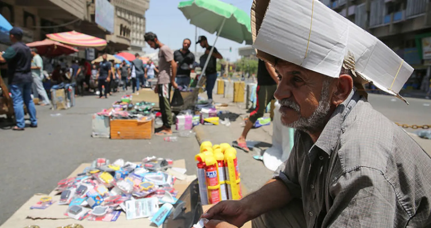 بائع عراقي يحمي رأسه بقبعة ورقية خلال موجة حر ضربت بغداد أمس (أ.ف.ب)