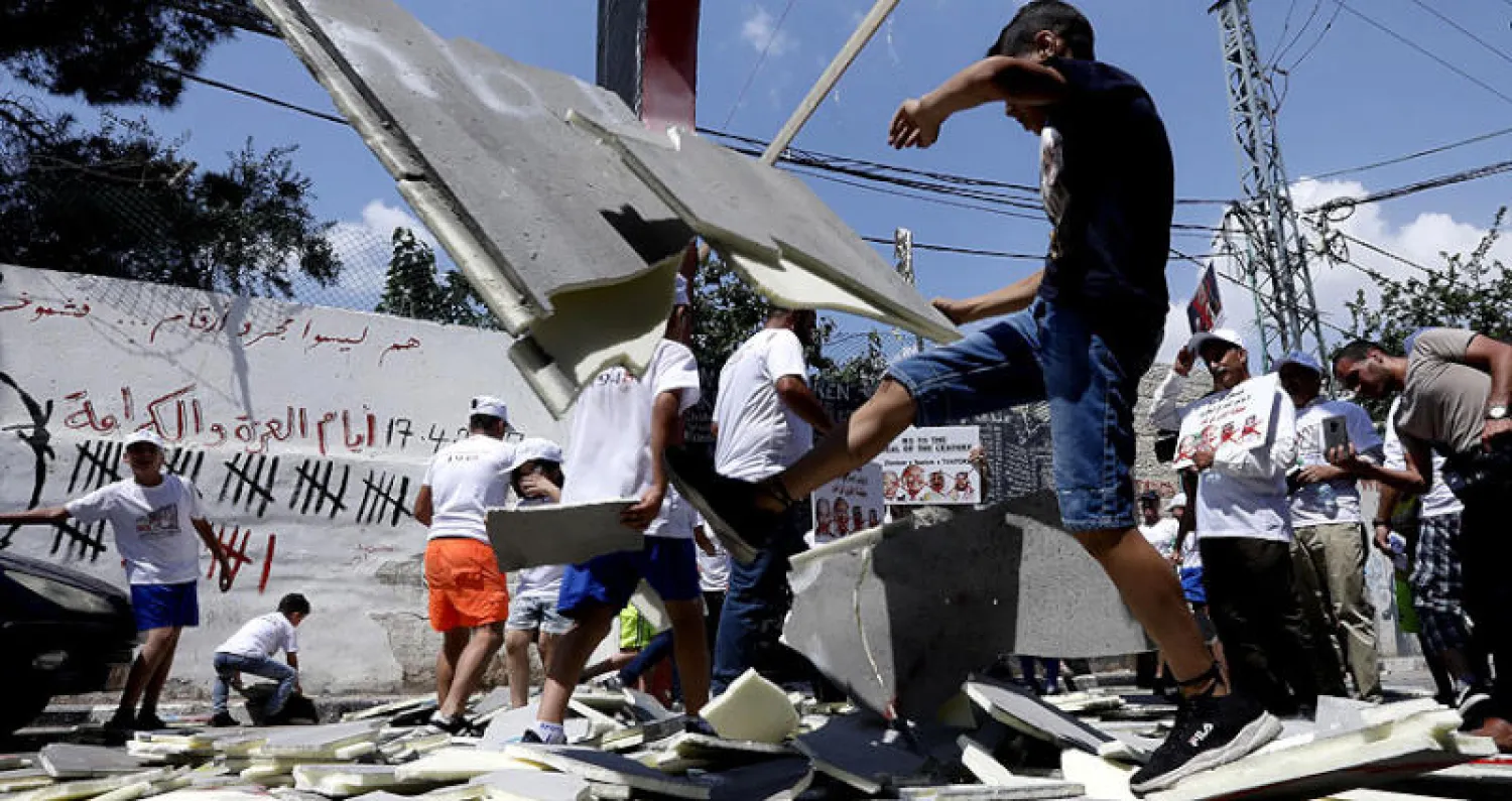 فلسطينيون يكسرون مجسماً للحائط الفاصل أثناء احتجاجات في بيت لحم أمس (إ.ب.أ)