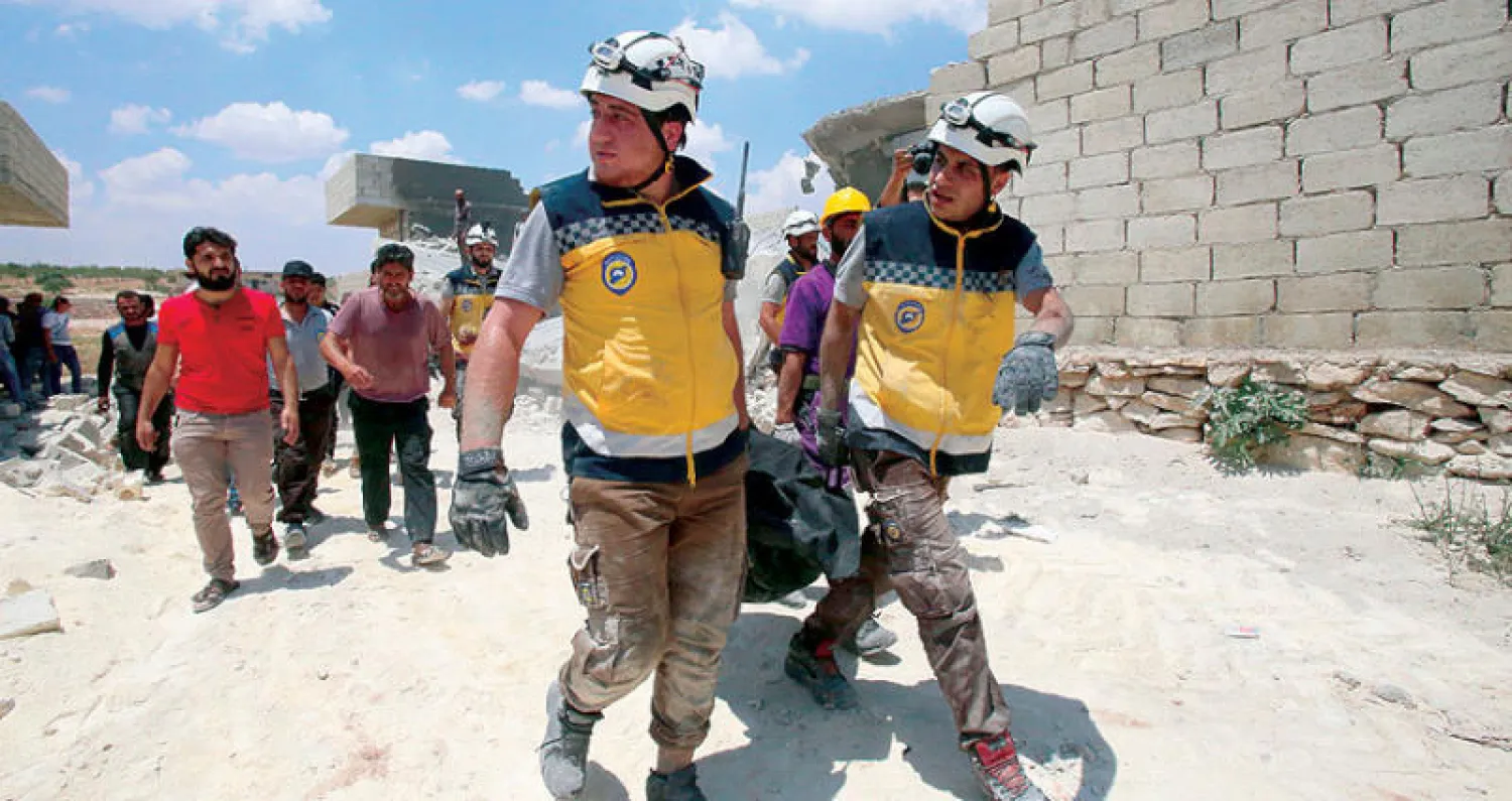 عناصر من الدفاع المدني ينتشلون جثة من بين أنقاض مبنى تهدم بفعل غارات جوية على مدينة معرة النعمان بمحافظة إدلب أمس (أ.ف.ب)