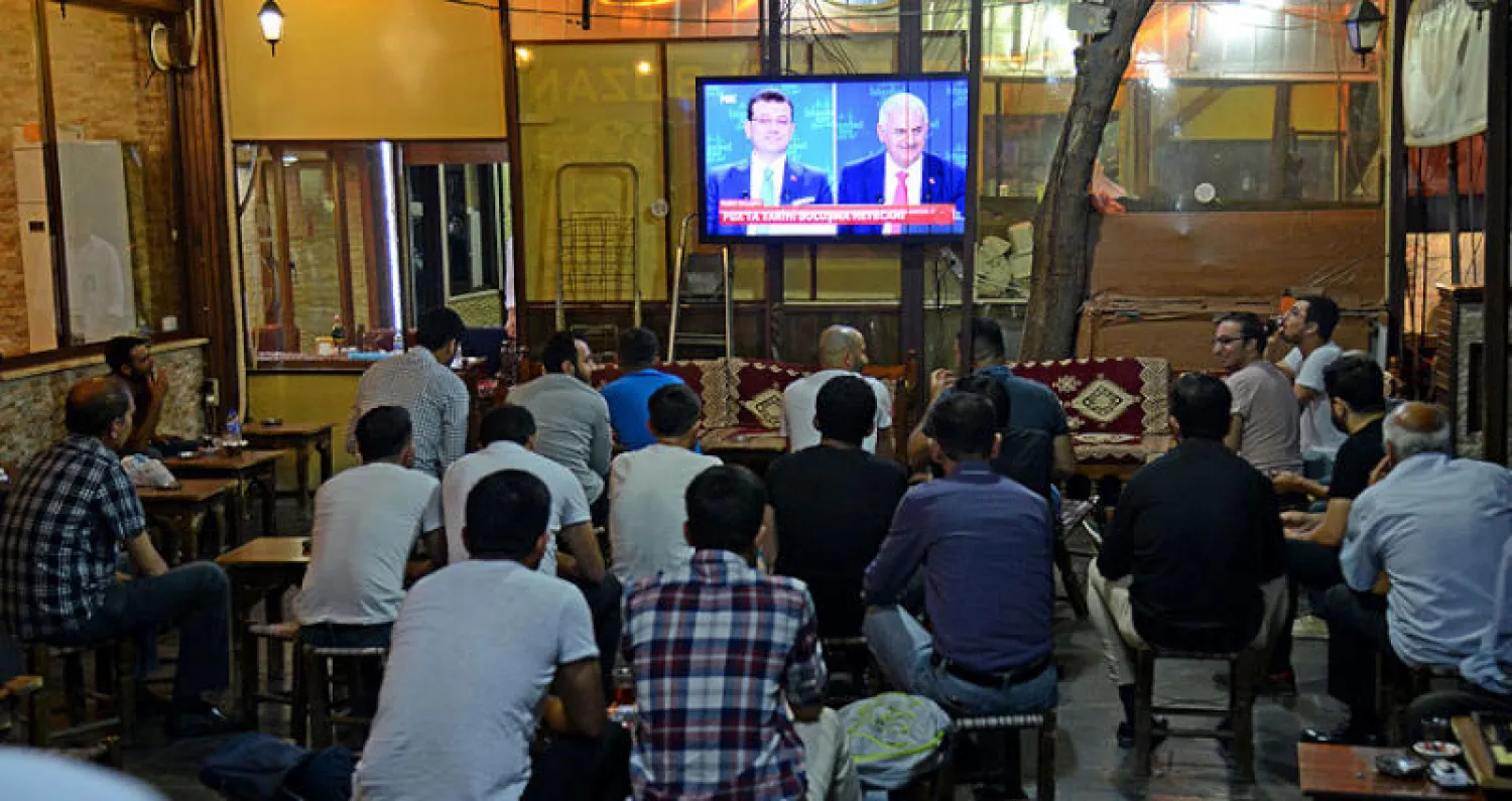 أتراك يتابعون المناظرة بين إمام أوغلو ويلدريم في مقهى بإسطنبول أول من أمس (أ.ف.ب)