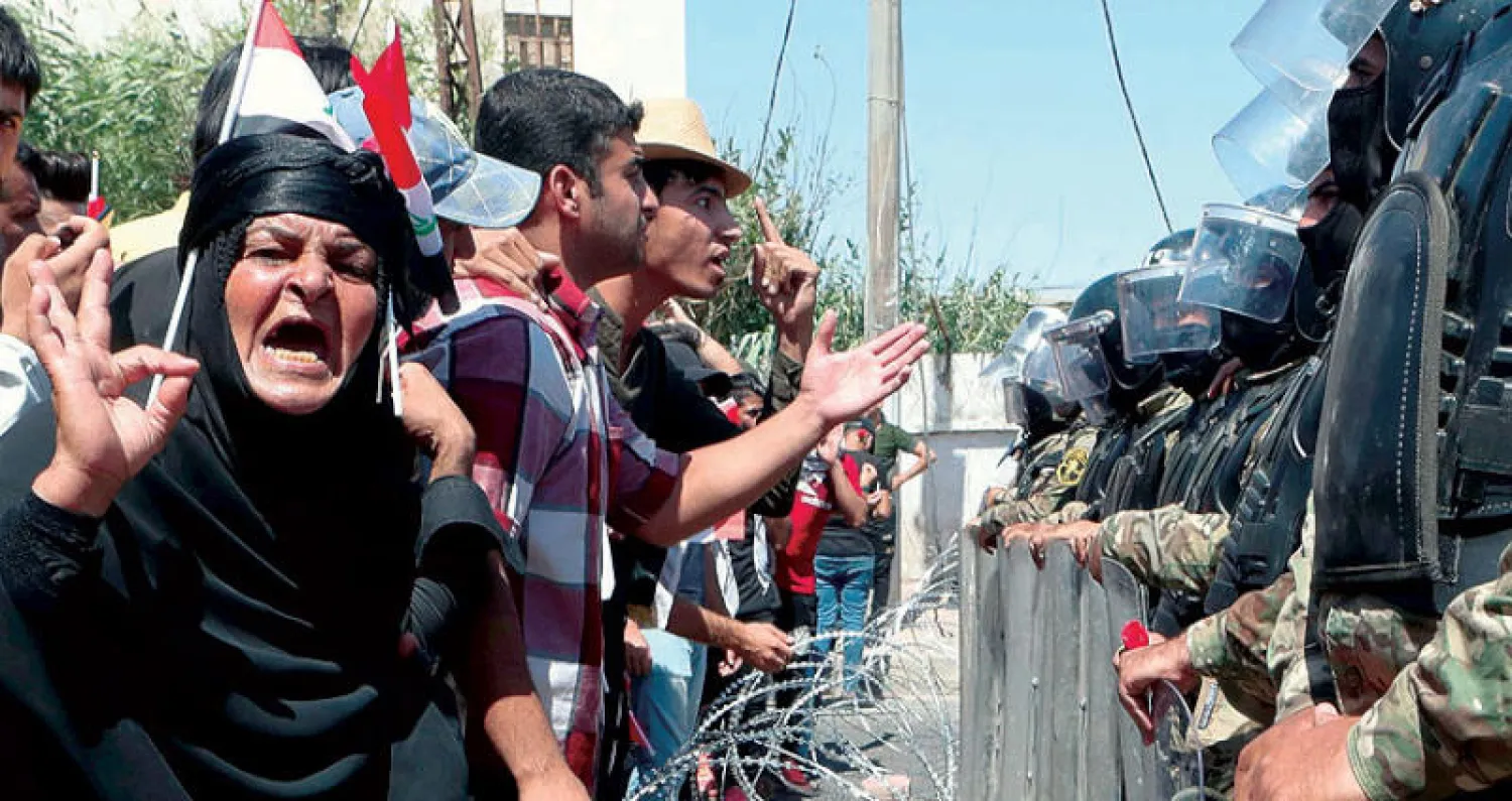 شرطة مكافحة الشغب تمنع متظاهرين من اقتحام مبنى مجلس محافظة البصرة (أ.ب)