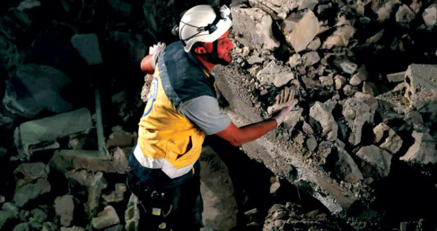 عنصر من الدفاع المدني يبحث عن قتلى أو جرحى بين أنقاض مبنى دمره قصف النظام السوري على بلدة سراقب بمحافظة إدلب أمس (أ.ف.ب)