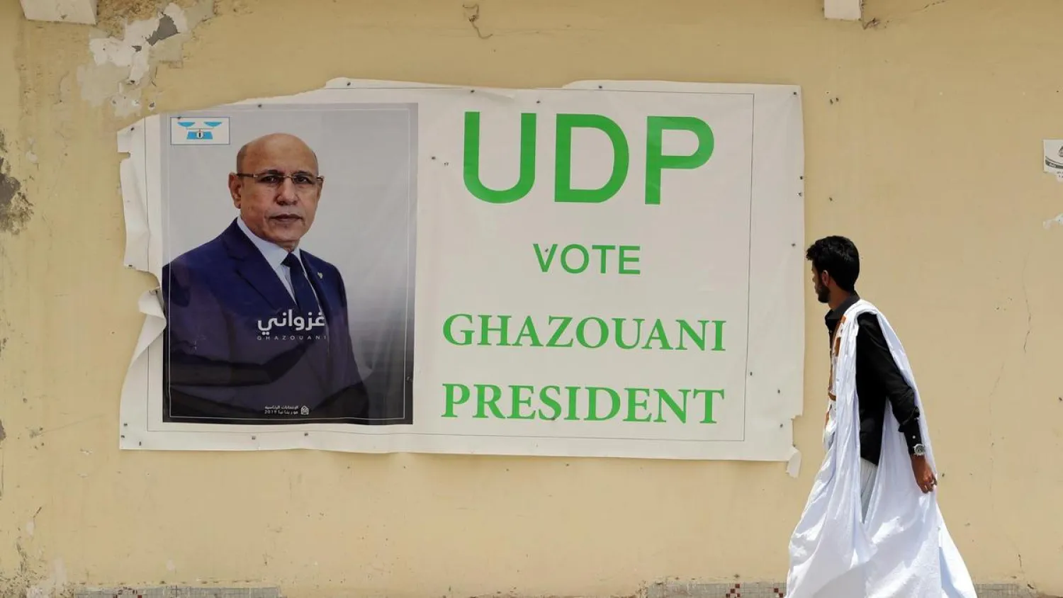 A man walks past an election poster of government candidate Mohamed Ould Ghazouani in a street of Nouakchott, Mauritania, June 20, 2019. (EPA)