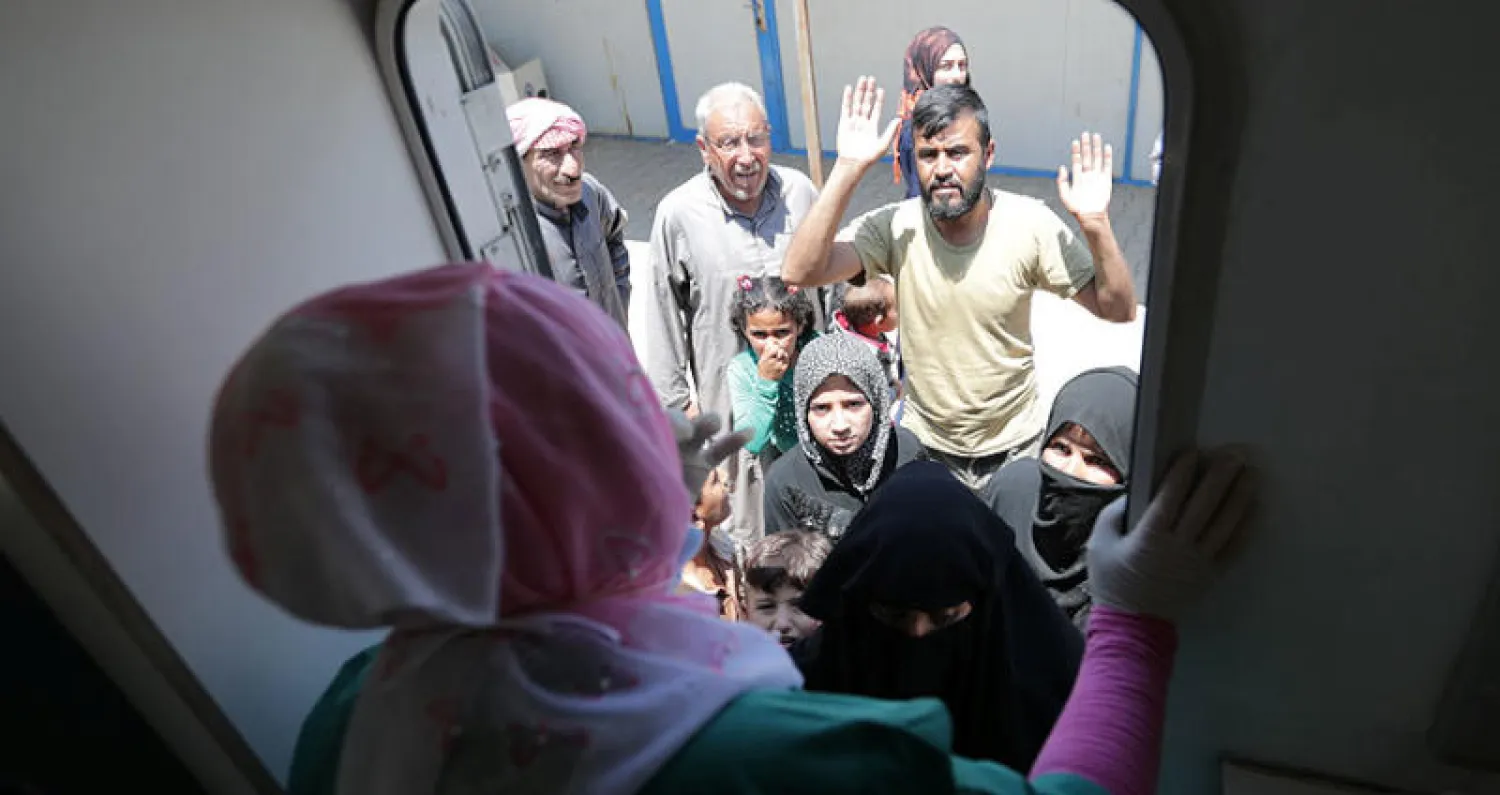 نازحون سوريون بانتظار دورهم أمام عيادة أسنان متنقلة في أعزاز قرب الحدود التركية (رويترز)