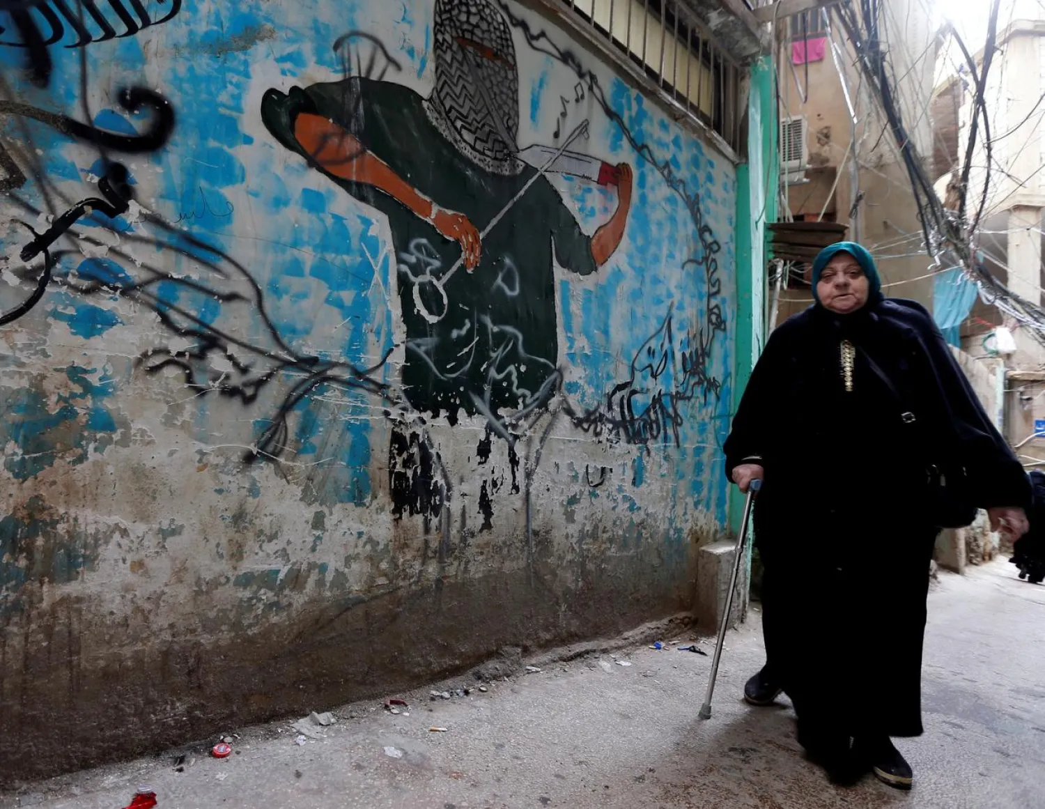 A woman walks past a graffiti in Burj al-Barajneh refugee camp in Beirut, Lebanon, January 29, 2018. (Reuters)