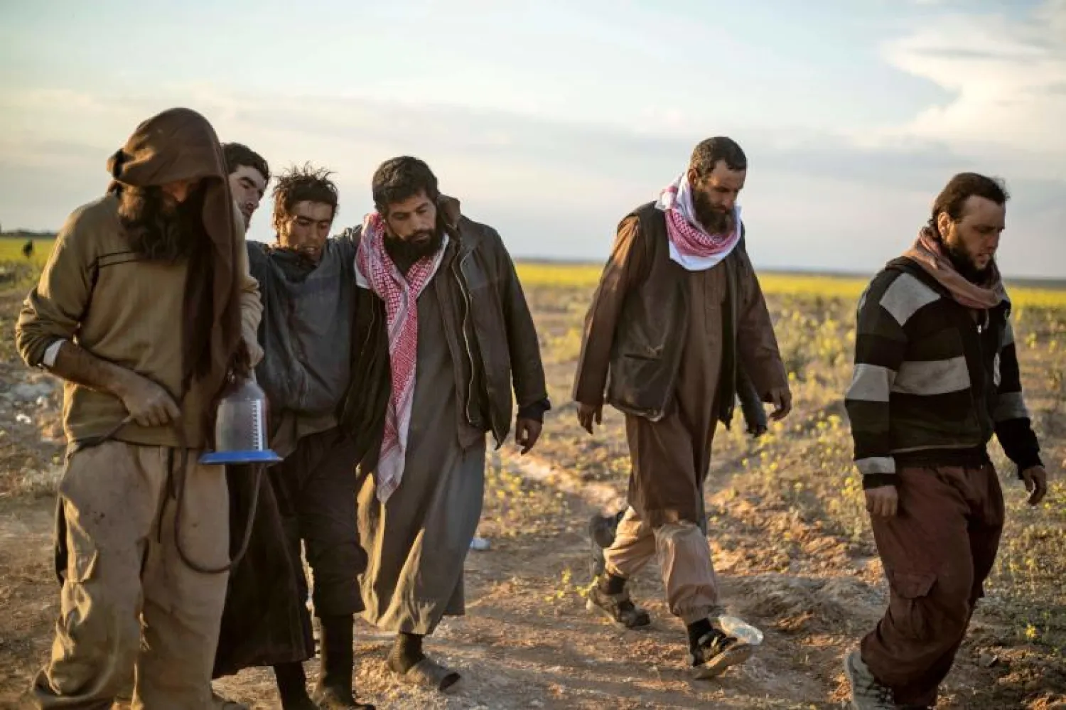 رجال يشتبه بأنهم من مقاتلي تنظيم «داعش» يمشون باتجاه نقطة تفتيش تديرها «قوات سوريا الديمقراطية» في دير الزور (أ.ف.ب)