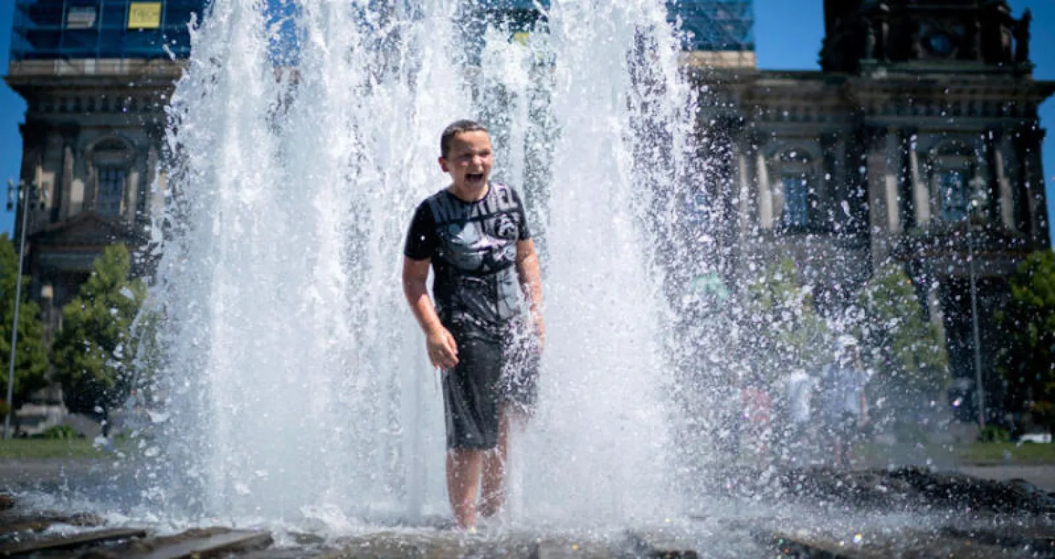صبي ينتعش في نافورة في برلين بعد وصول الحرارة إلى 39 درجة مئوية (أ.ف.ب)