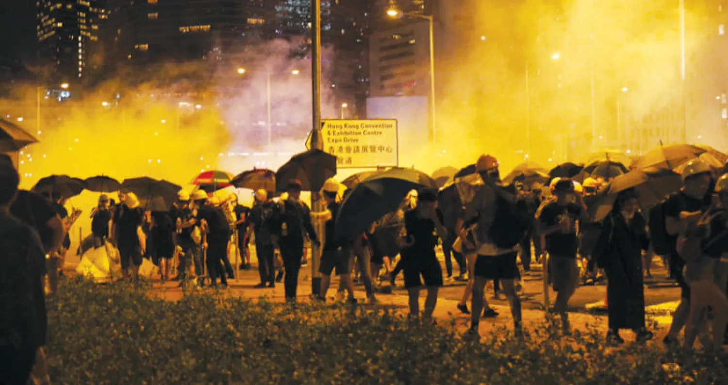 جانب من المواجهات بين المحتجين وقوات الأمن خارج البرلمان في هونغ كونغ أمس (إ.ب.أ)