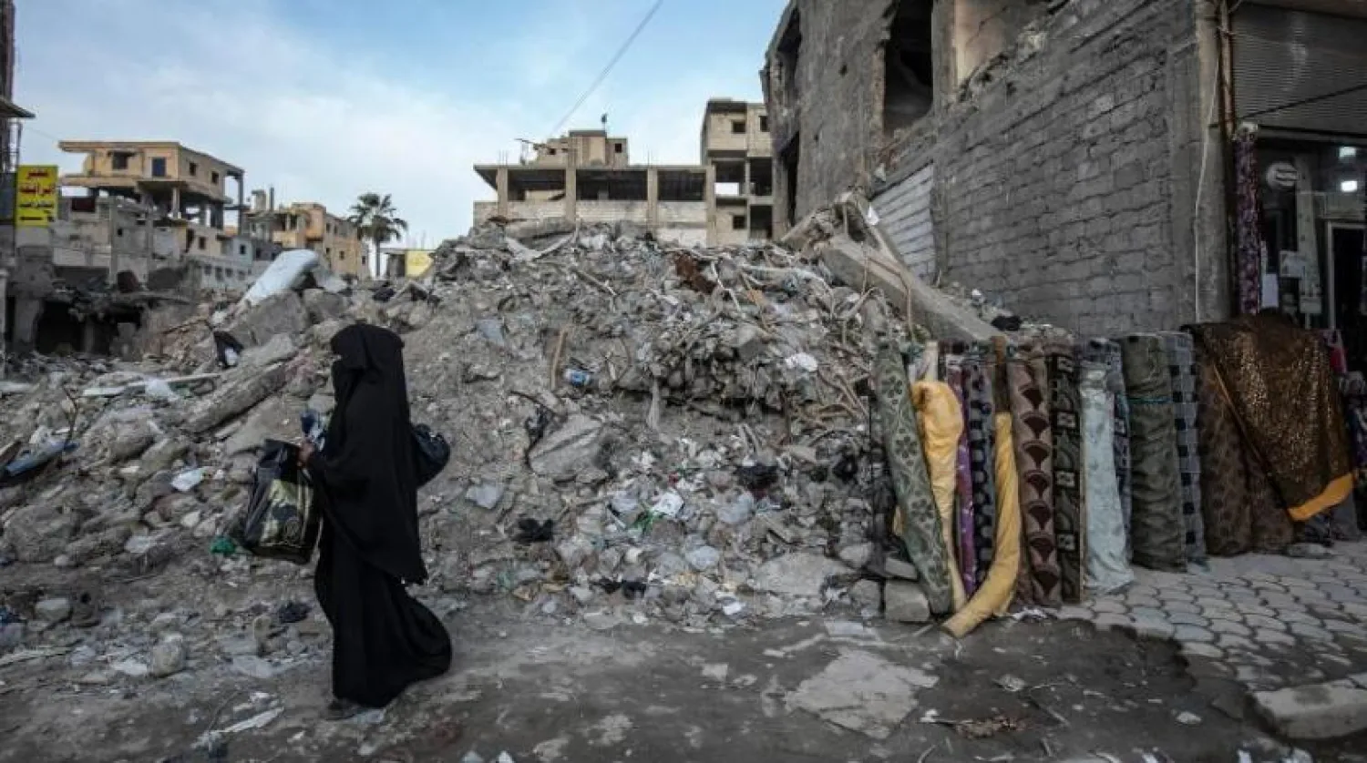 Suriyeli bir kadın Rakka'da yıkılmış bir evin enkazı arasında yürüyor (AFP)