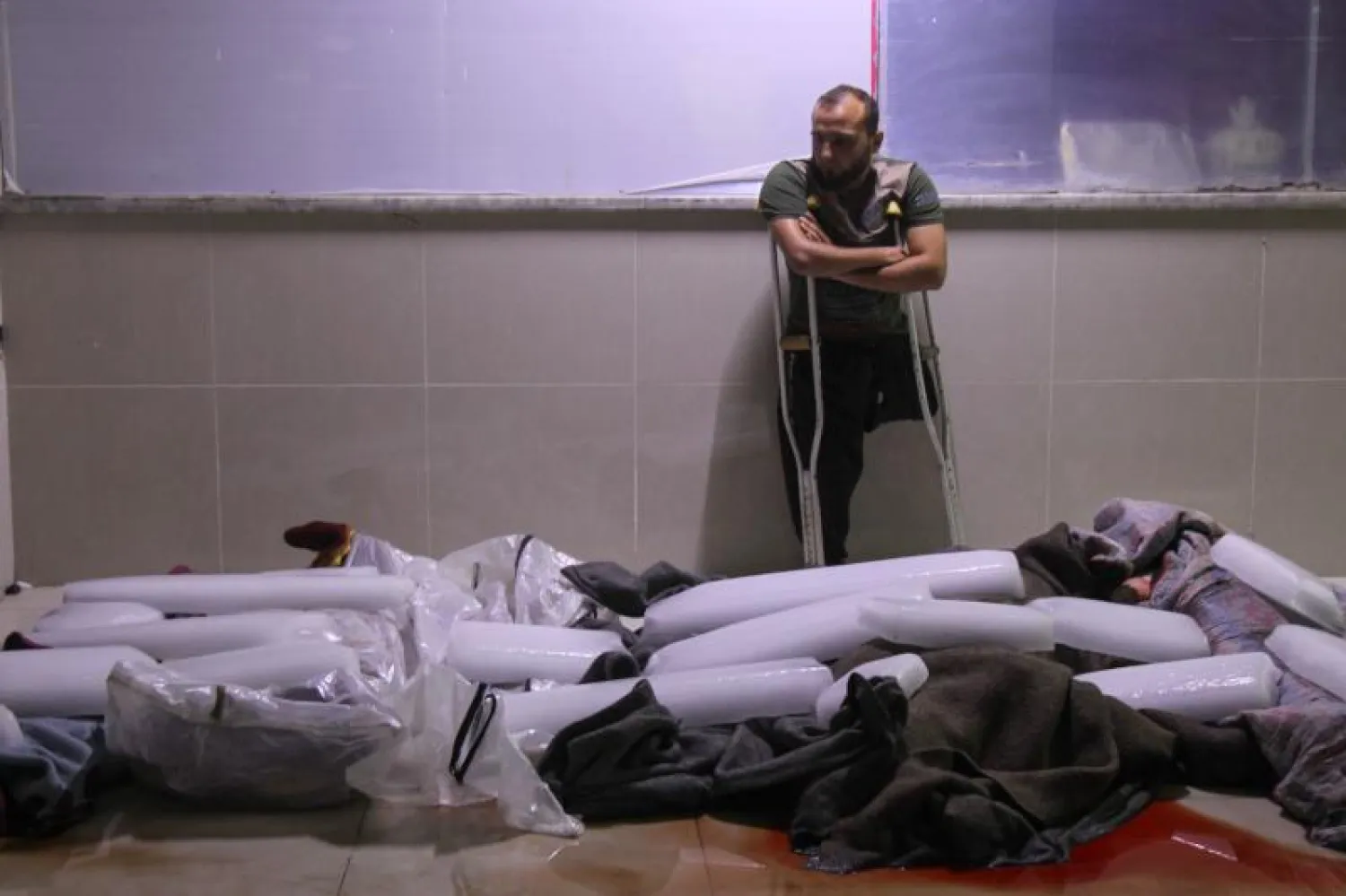 سوري ينظر إلى عدد من جثث المدنيين قتلوا بغارات جوية شنها النظام السوري بإدلب (أ.ف.ب)