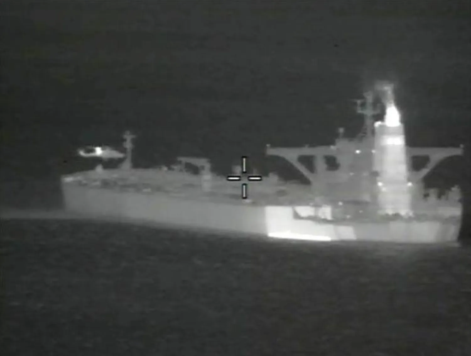 A helicopter hovers near the Iranian oil tanker Grace 1 off Gibraltar, according to Britain’s Ministry of Defence, in a night vision photograph released July 4, 2019. British Royal Marines seized the Grace 1 tanker on Thursday for trying to take oil to Syria in violation of European Union sanctions. MoD/Handout via REUTERS