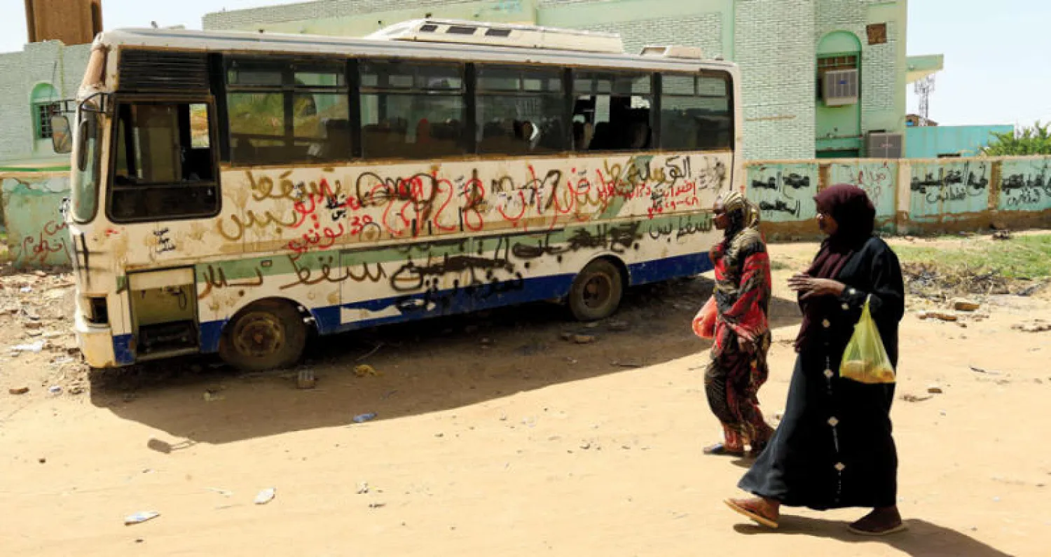 امرأتان تمران بالقرب من حافلة كتبت عليها عبارات مؤيدة للثورة ومنددة بالنظام السابق (رويترز)