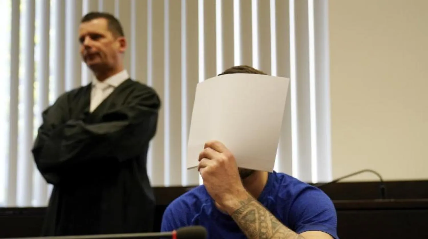 Ali Bashar (R) covers his face in front of the cameras upon entering the courtroom, as his lawyer Martin Reineke looks on, on July 10, 2019 in Wiesbaden, western Germany. Boris Roessler / POOL / AFP