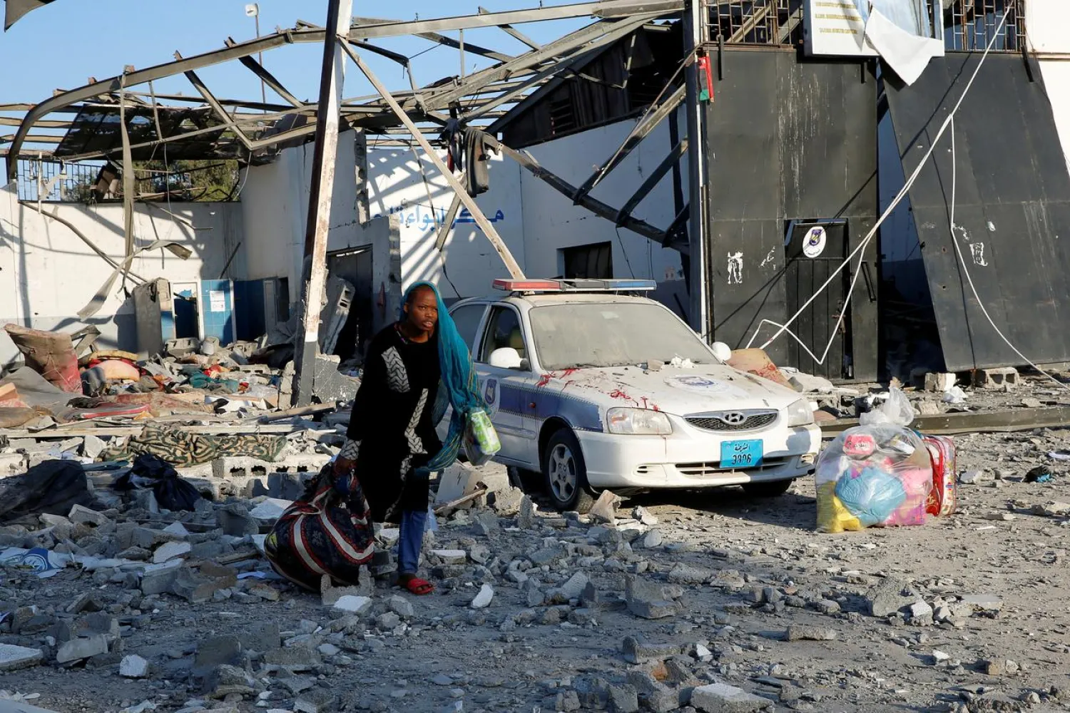 A migrant picks up her belongings from among rubble at a detention center that was hit by an airstrike in the Tajoura suburb of the Libyan capital of Tripoli, Libya July 3, 2019. REUTERS/Ismail Zitouny/File Photo