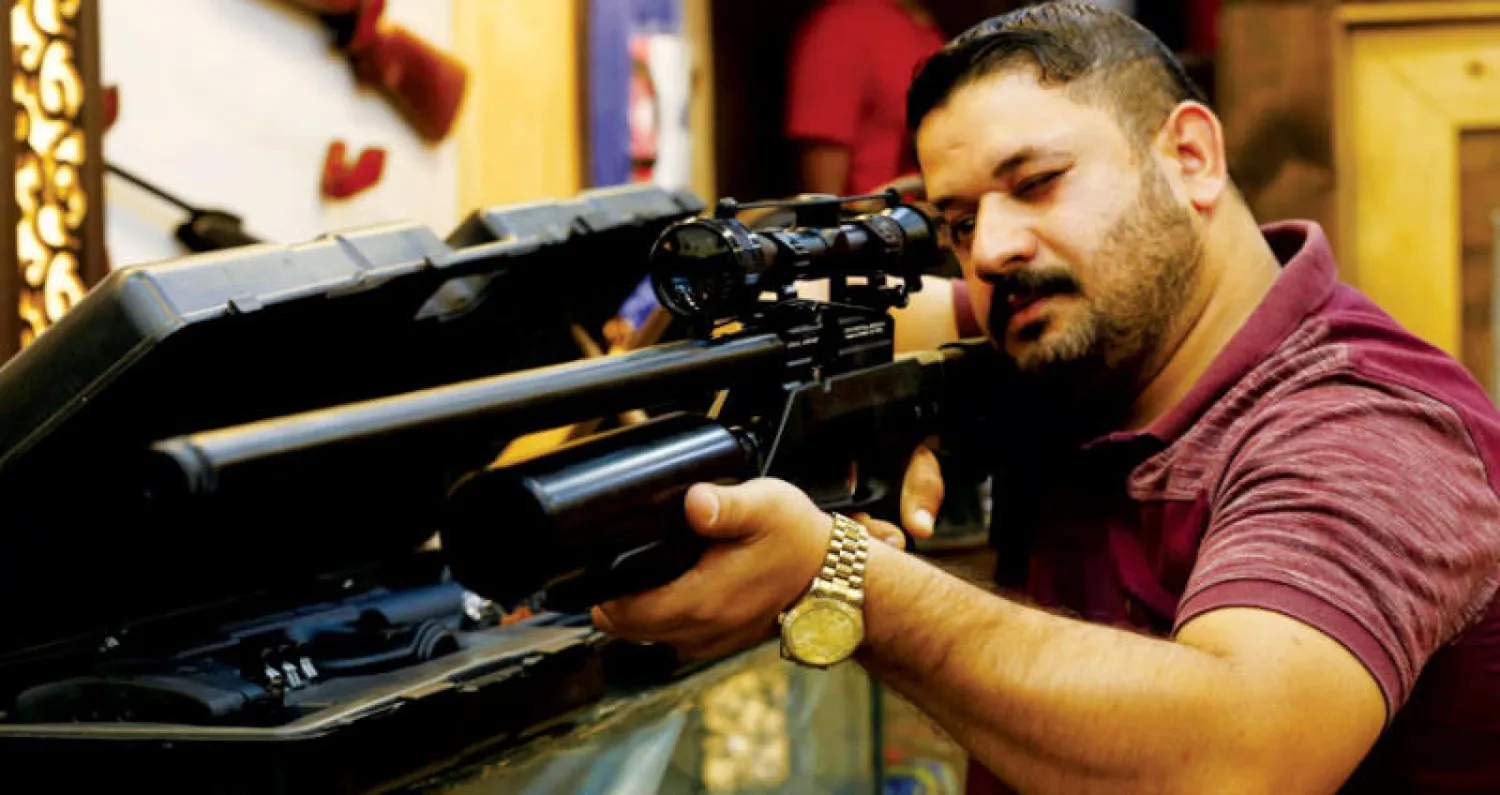 عراقي يختبر قطعة سلاح في متجر ببغداد (رويترز)