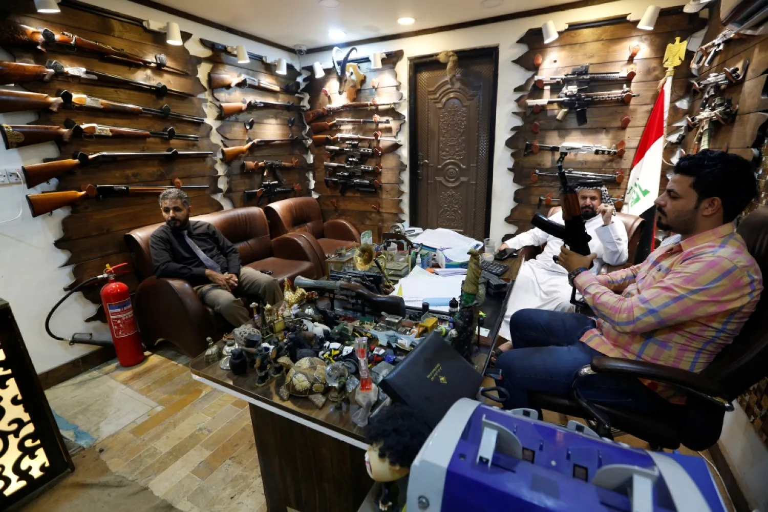 A shop owner, right, shows a weapon to customers at a weapons shop in Baghdad. Reuters file photo