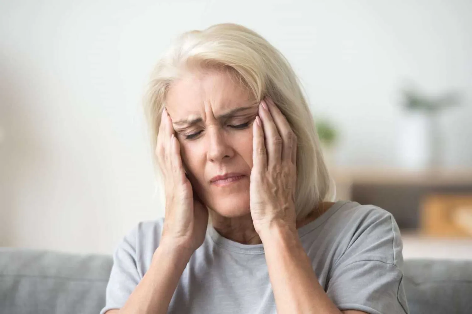 Upset middle aged woman massaging temples. Getty
