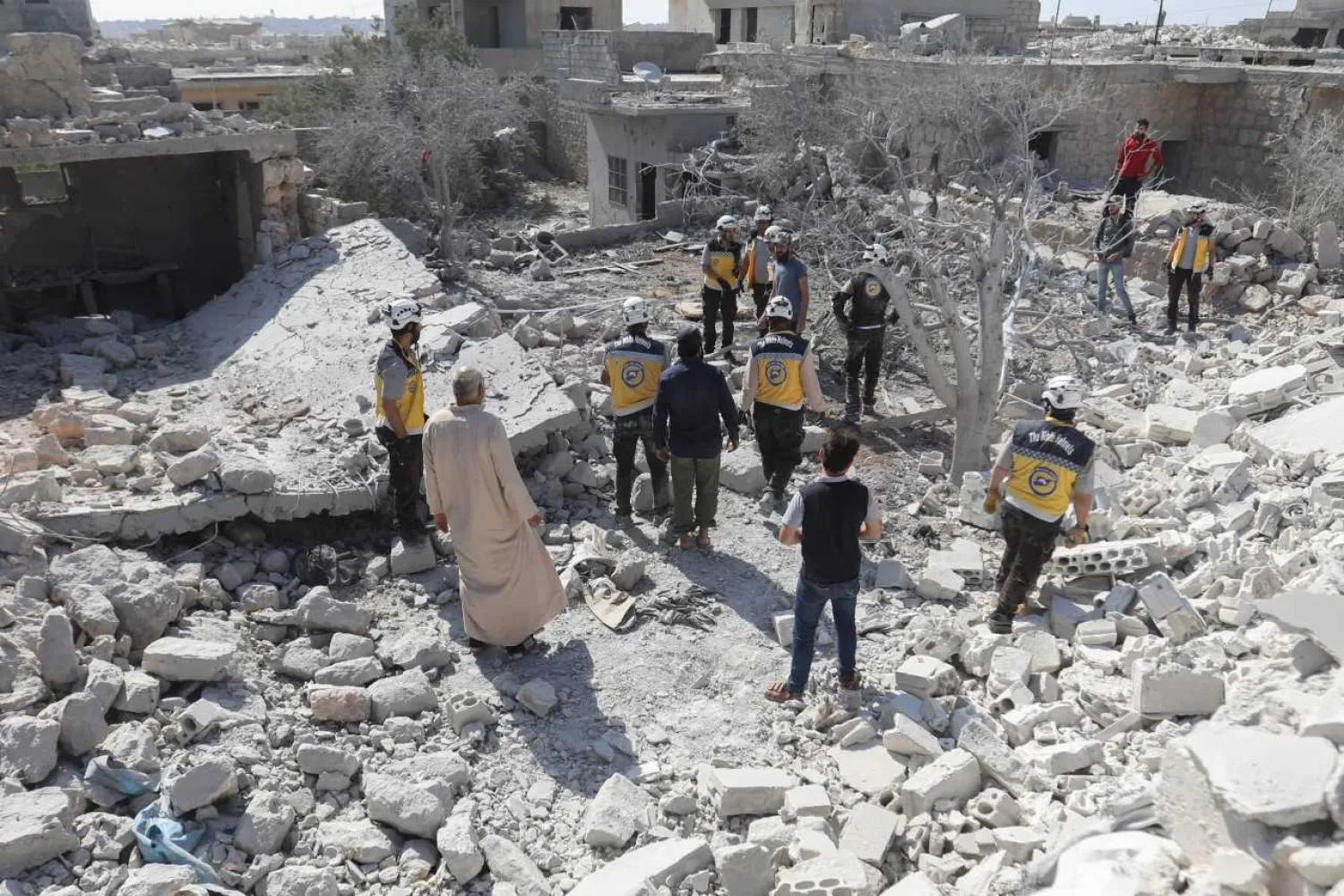 Members of the Syrian Civil Defense (White Helmets) and civilians gather following a reported regime airstrike on the village of Kafriya, in Syria's Idlib province, on July 13, 2019. Omar HAJ KADOUR / AFP