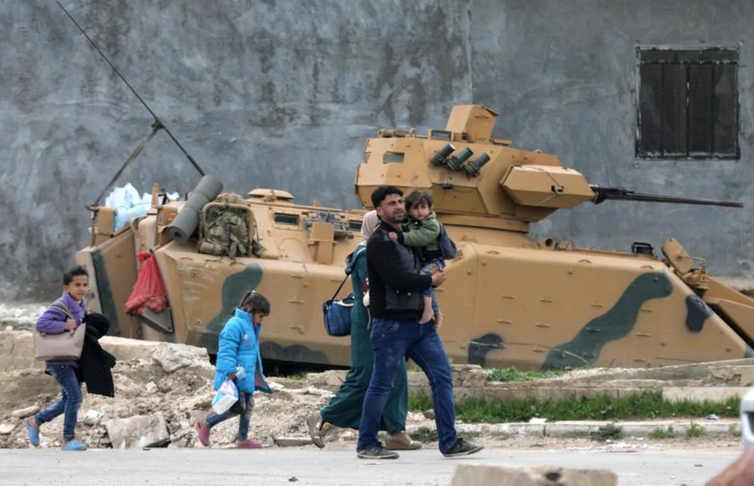  A family walks past a military vehicle belonging to Turkish-backed Free Syrian Army fighters after the capture of Khaldieh village, in eastern Afrin, Syria March 10,2018. REUTERS/ Khalil Ashawi