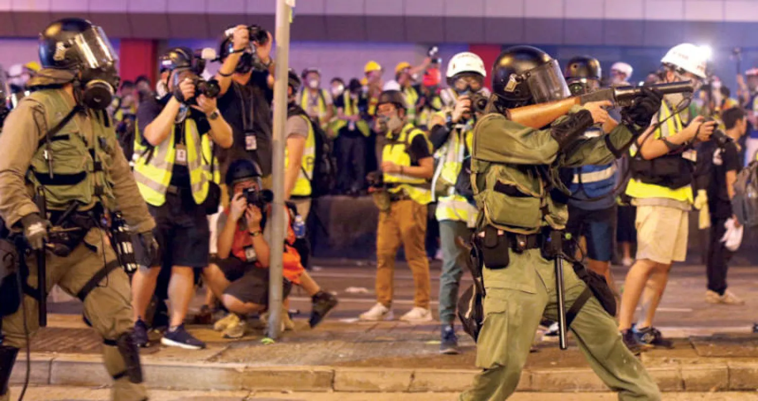 شرطة مكافحة الشغب تستعد لإطلاق الغاز المسيل للدموع في مواجهة مع المتظاهرين بهونغ كونغ أمس (إ.ب.أ)