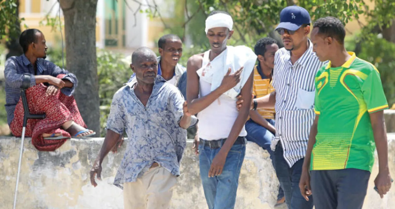 أقارب يساعدون أحد جرحى التفجير الإرهابي بالعاصمة مقديشو أمس الذي تبنته «حركة الشباب المجاهدين» التي بايعت «القاعدة»... (رويترز)