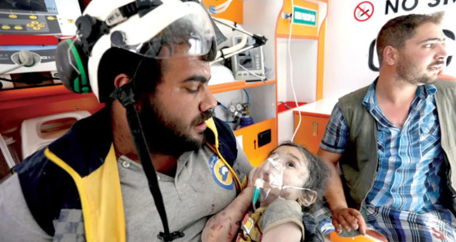 عنصر من «الدفاع المدني» يسعف طفلة بعد قصف معرة النعمان في إدلب أمس  (أ.ف.ب)