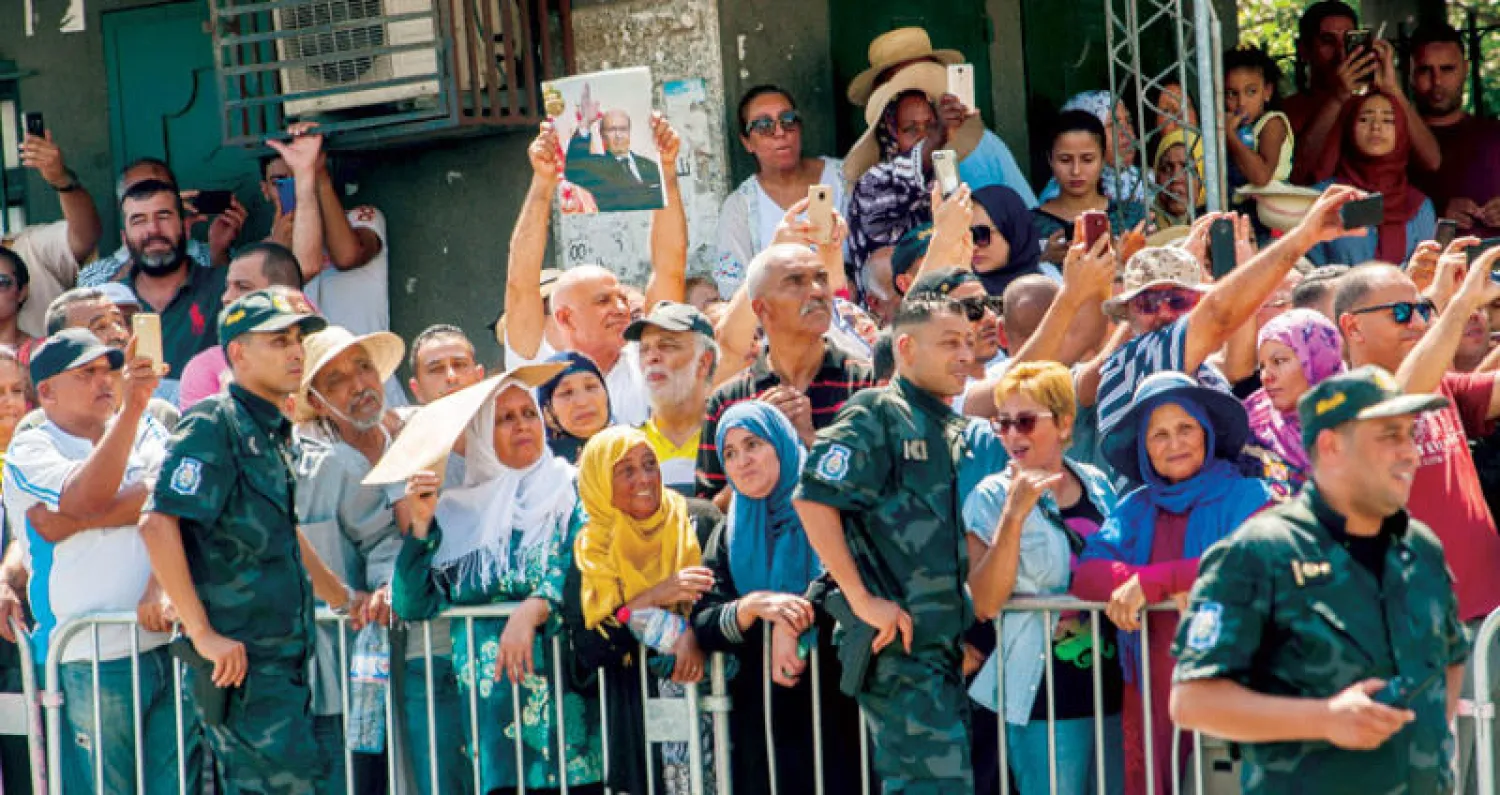 تونسيون يبكون رئيسهم في انتظار مرور السيارة التي تحمل نعشه إلى قصر قرطاج قبل دفنه (أ.ب)