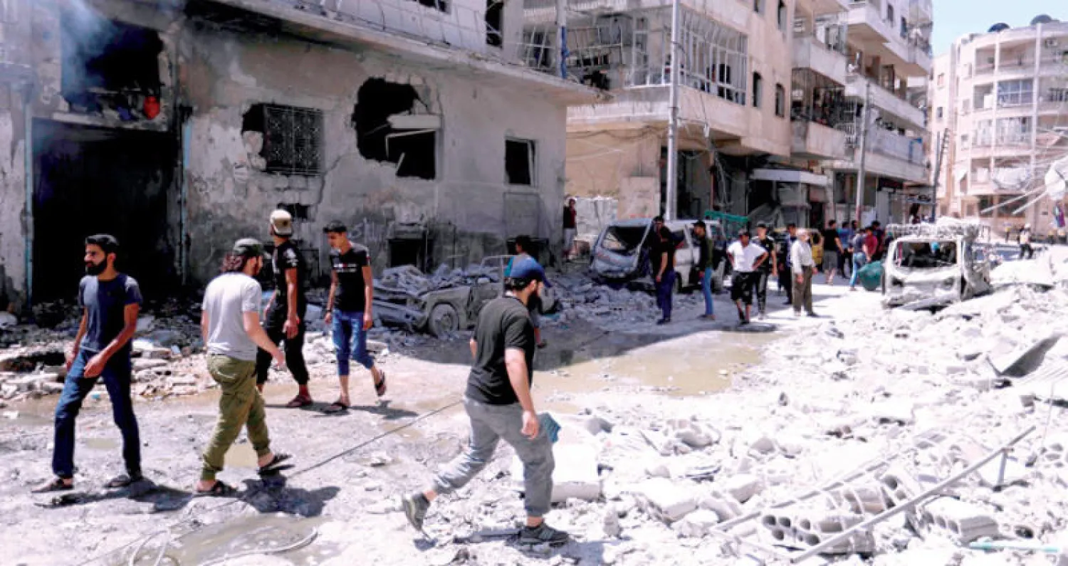 سوريون وسط الخراب بعد غارة لطيران النظام على أريحا في إدلب أمس (أ.ف.ب)