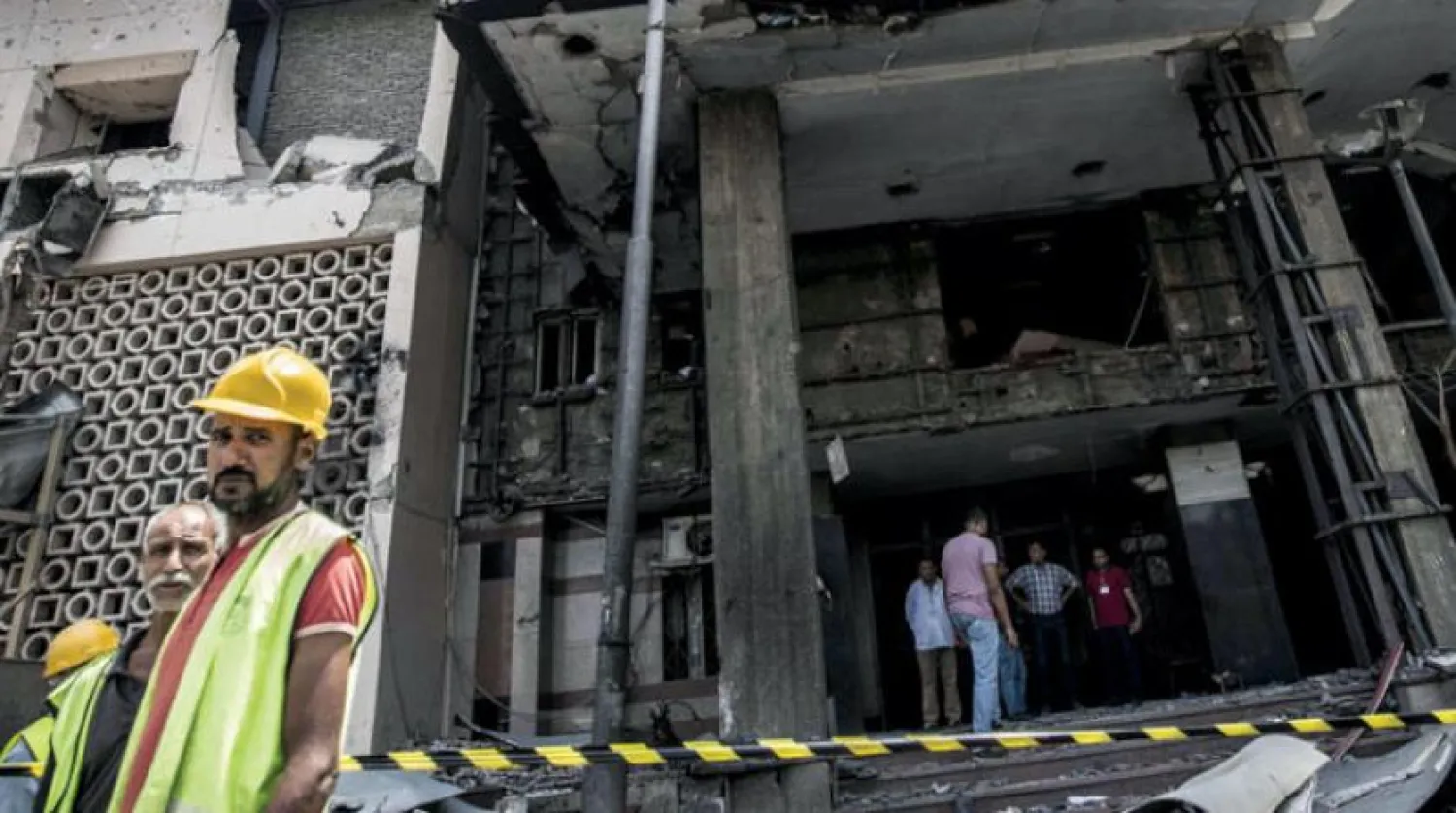 مصريون أمام المعهد القومي للسرطان في العاصمة القاهرة الذي تدمر مدخله بعد وقوع عمل إرهابي على بعد أمتار منه أدى إلى سقوط عشرات القتلى والجرحى أمس (أ.ف.ب)