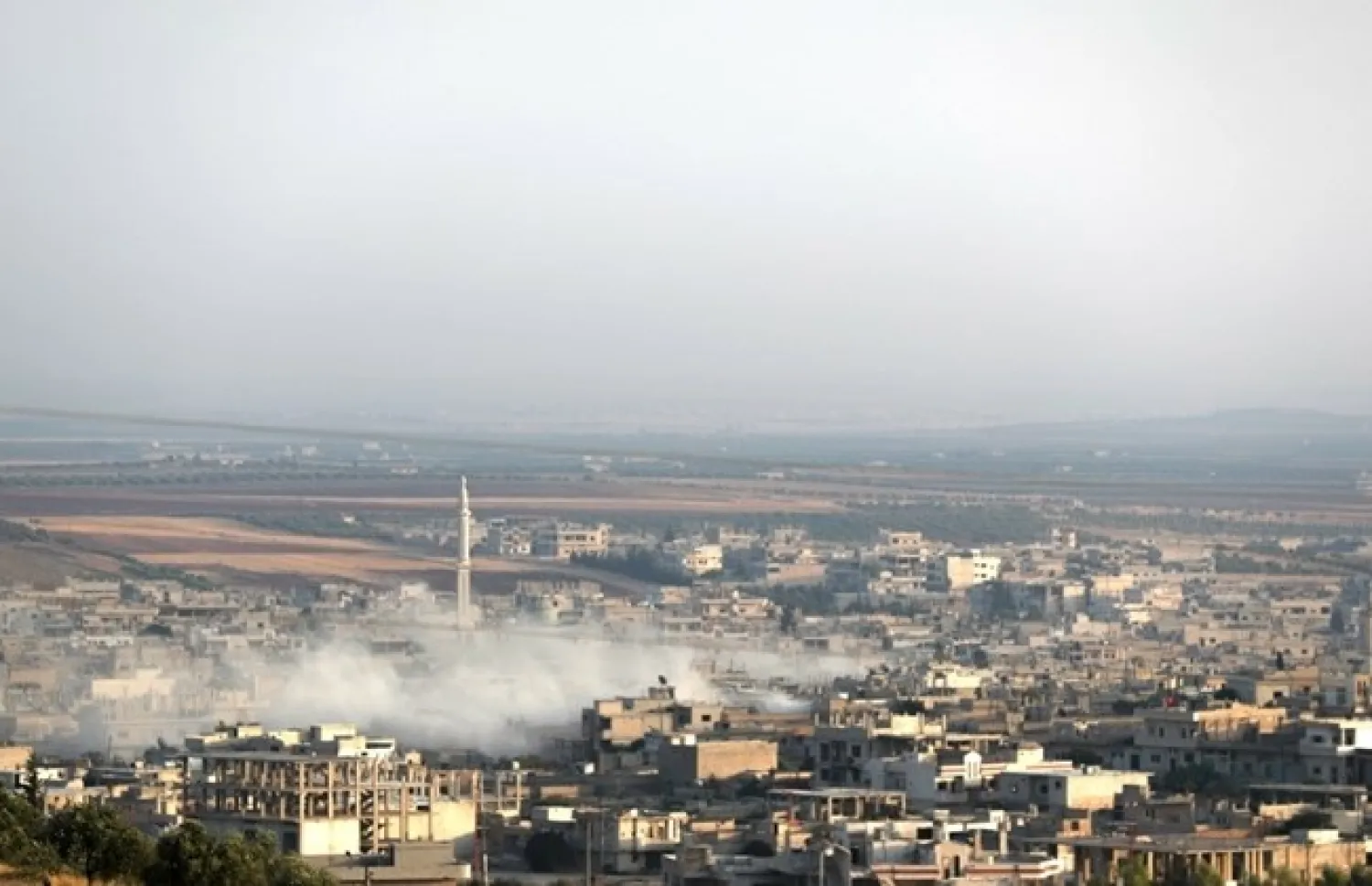 This picture taken on August 5, 2019 shows smoke billowing above buildings during a reported air strike by pro-regime forces on Khan Sheikhun in the south of the northwestern Syrian province of Idlib. / AFP / Omar HAJ KADOUR

