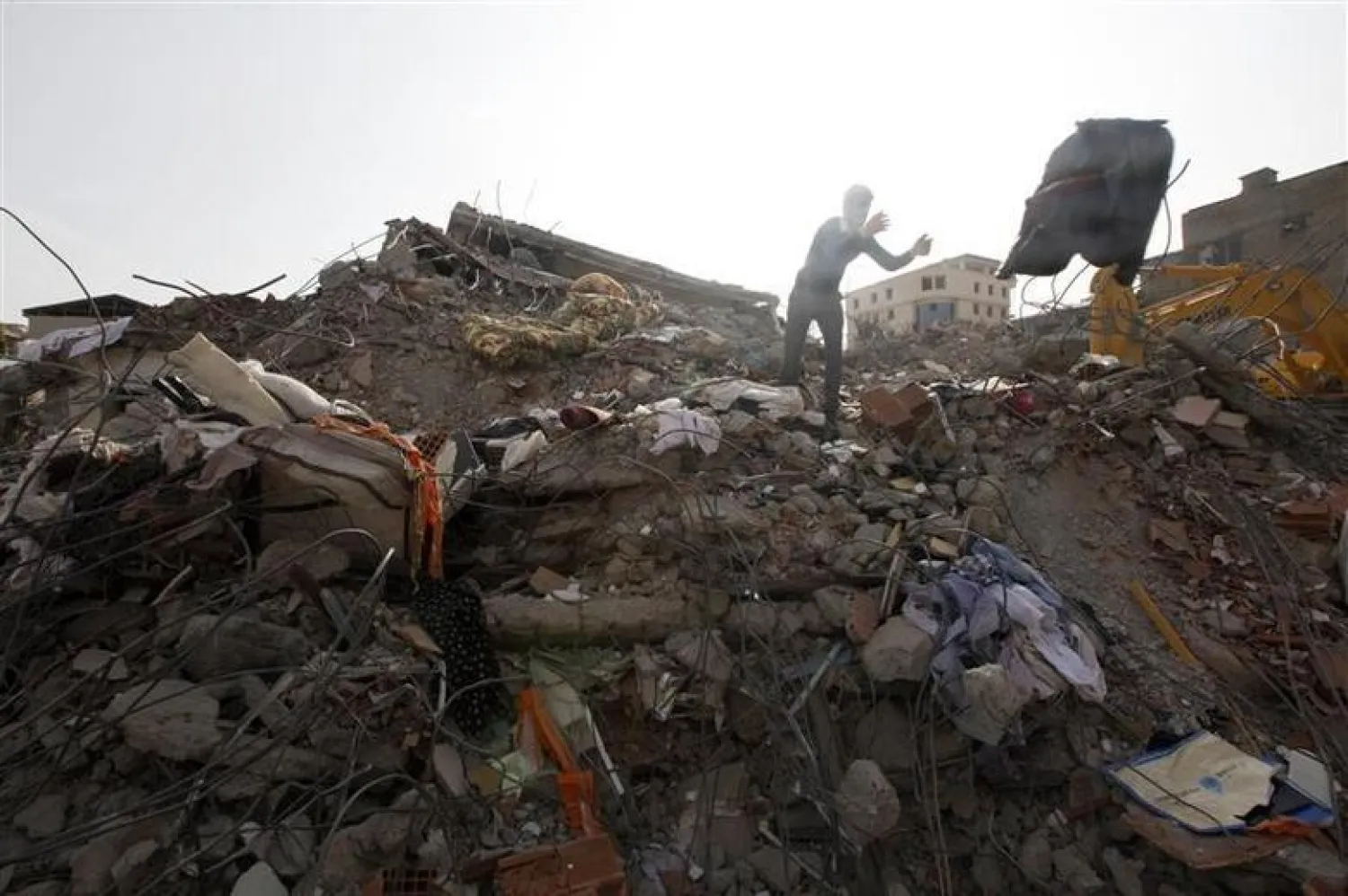 A resident, affected by the recent earthquake, collects belongings from a collapsed building in the eastern Turkish city of Van October 26, 2011. REUTERS/Umit Bektas

