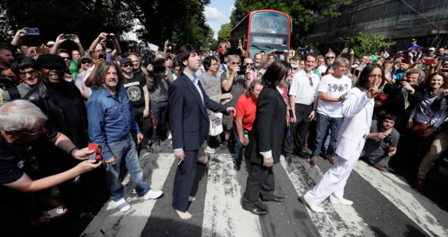 تجمع من الأشخاص يقلدون البيتلز في عبور المشاة (أ.ب)