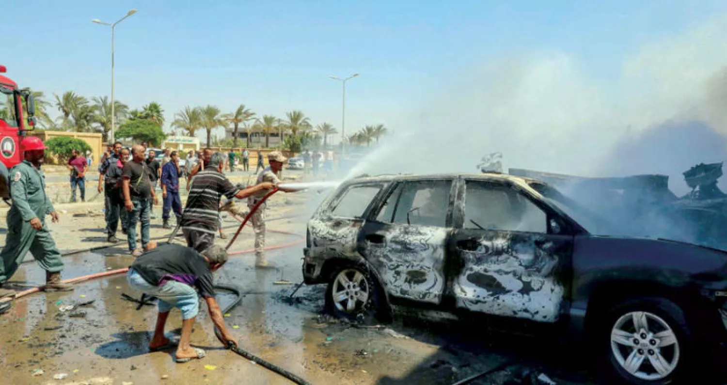 رجال إطفاء يحاولون إخماد الحريق داخل السيارة المفخخة بعد انفجارها وسط مدينة بنغازي (أ.ف.ب)