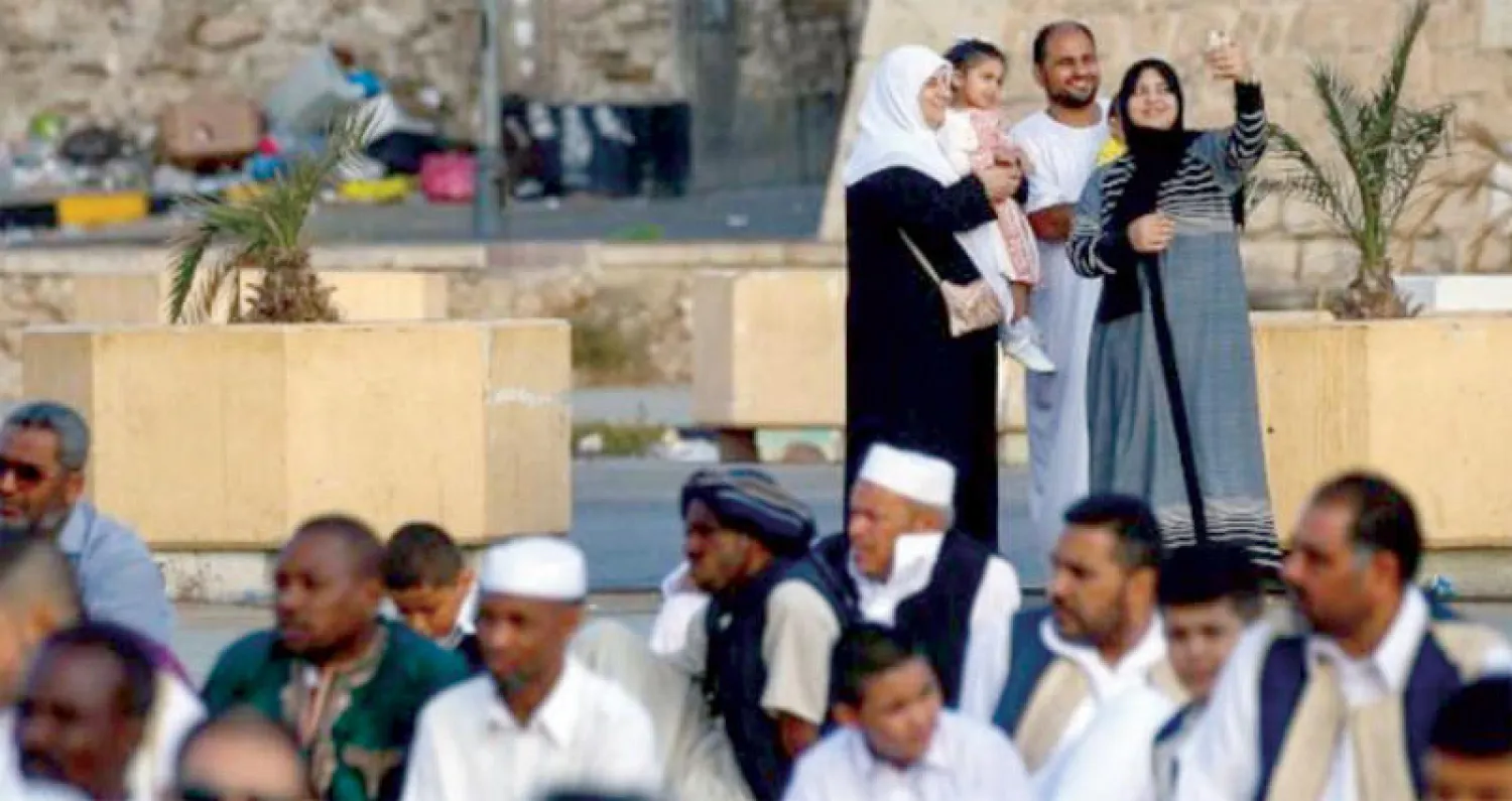 ليبيون يستمعون لخطبة العيد في ميدان الشهداء بطرابلس، بينما أسرة ليبية تلتقط صورة سيلفي (أ ف ب)