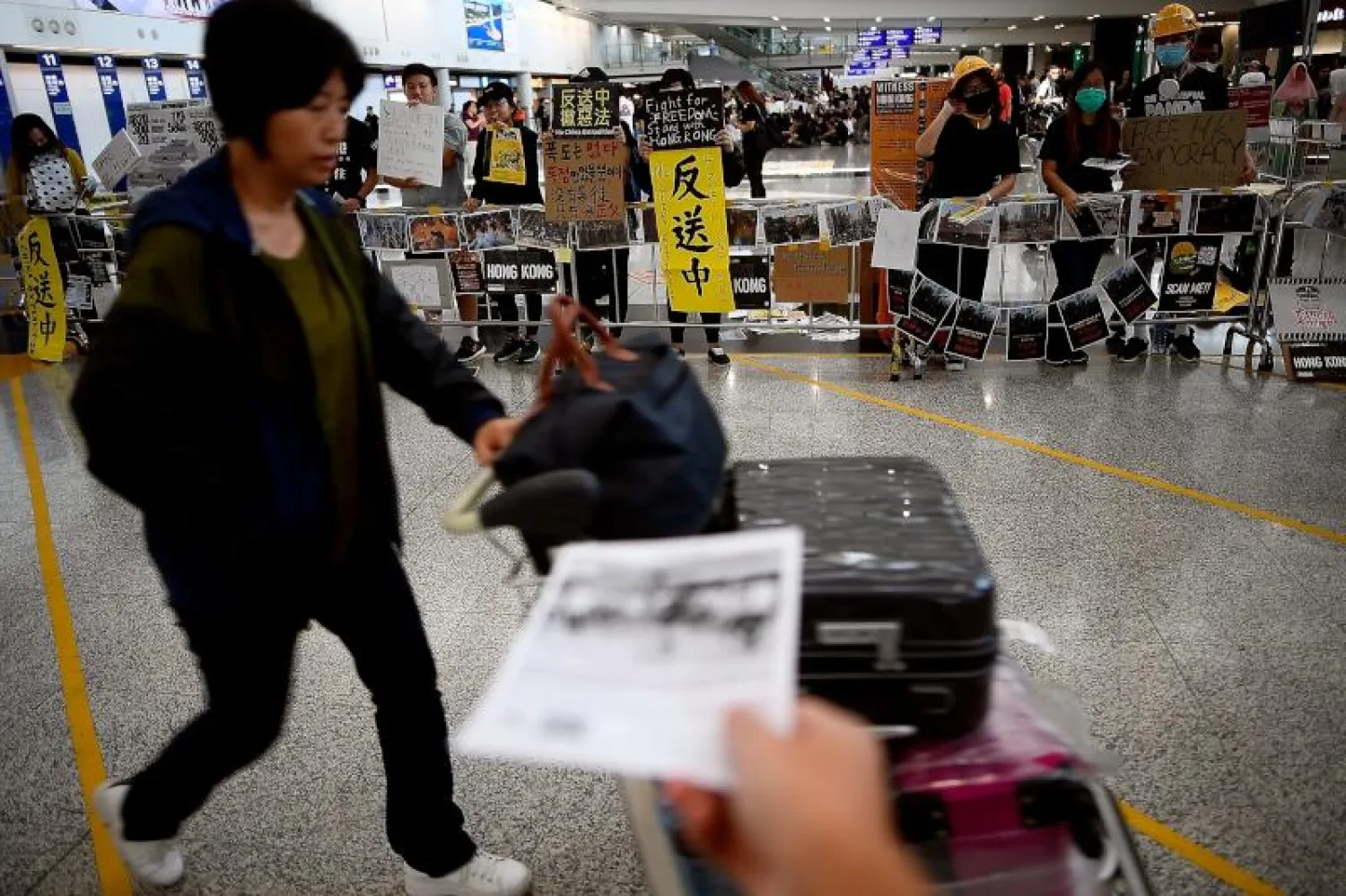 متظاهر يوزّع منشورات على الواصلين إلى مطار هونغ كونغ (أ.ف.ب)