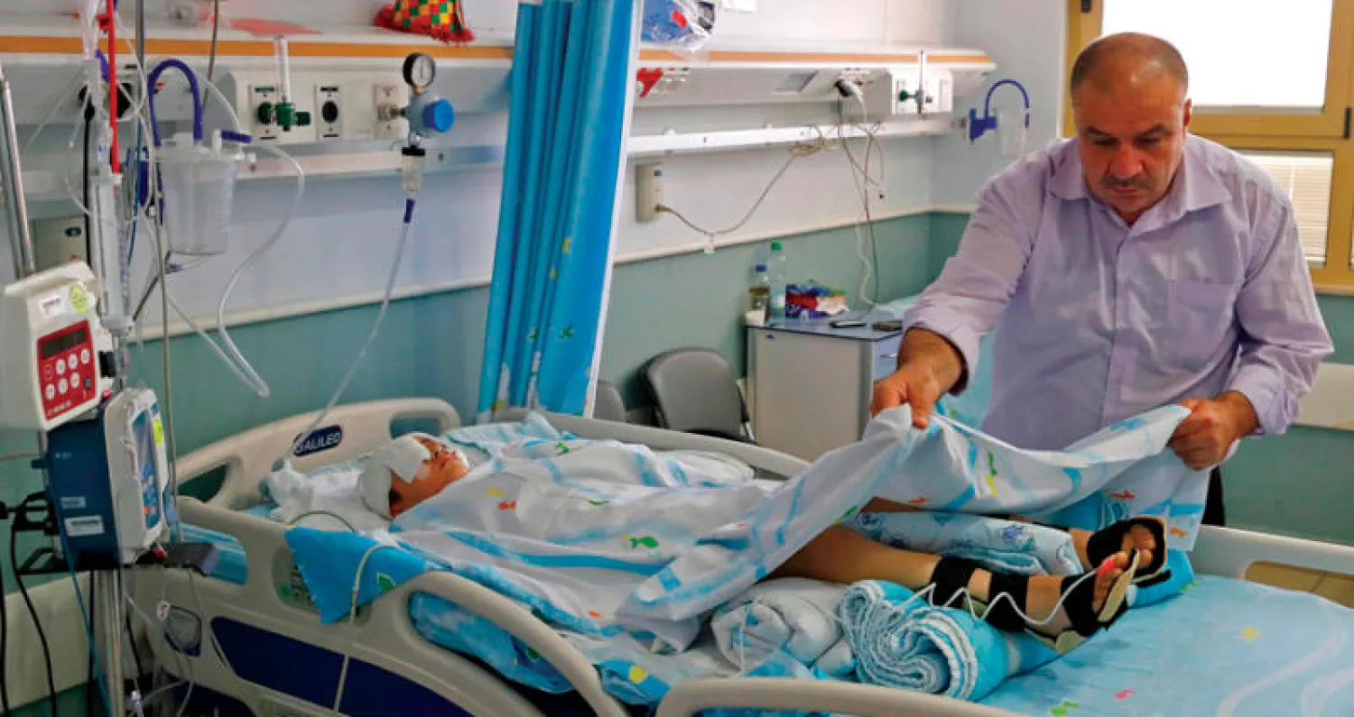 طفل فلسطيني يتلقى العلاج من إصابة بطلق ناري في اشتباكات شهدتها قرية كفردوم  (أ.ف.ب)