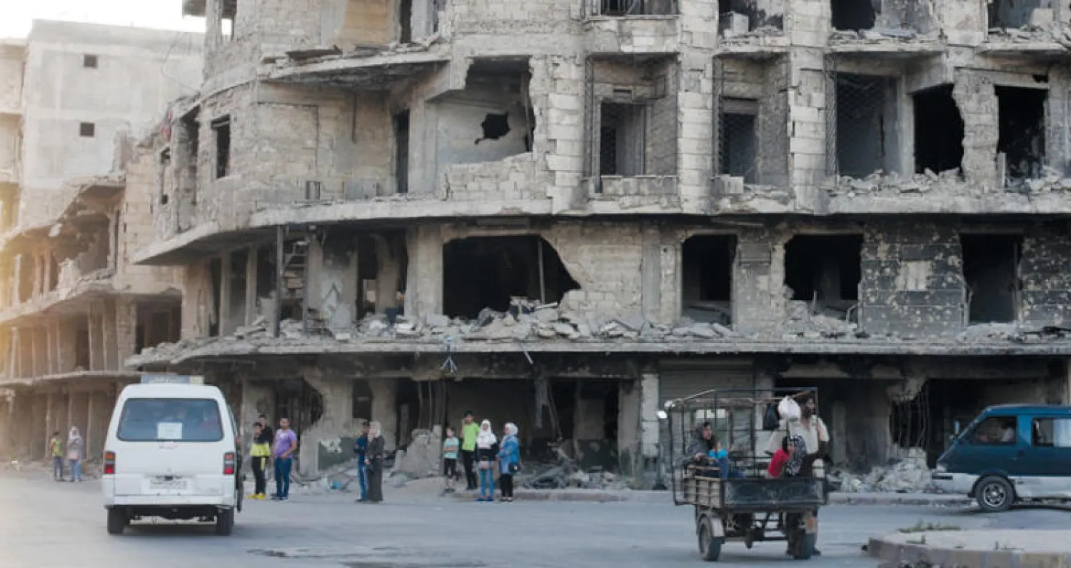 مواطنون في حلب قرب أبنية مدمَّرة (أ.ب)