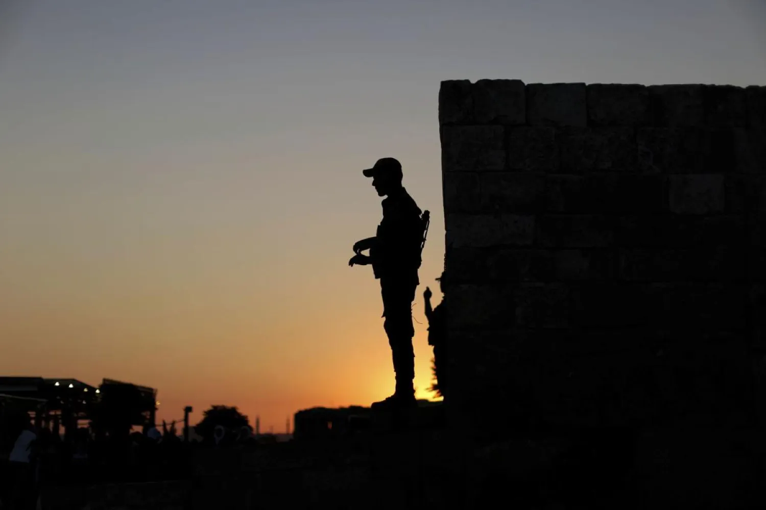 In this Saturday, July 27, 2019 photo, a woman walks in front of the ancient Citadel with a giant picture of Syrian President Bashar Assad, in Aleppo, Syria. (AP Photo/Hassan Ammar)