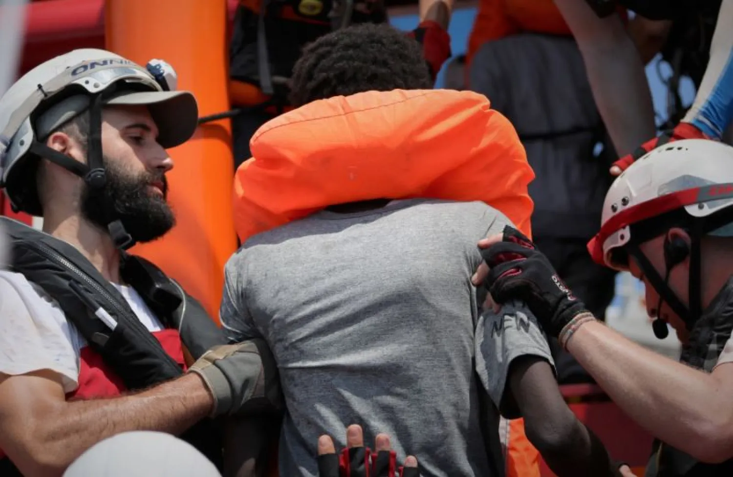 In this photo taken Saturday and released Sunday, Aug. 11, 2019, a rescue team of the Ocean Viking ship, operated by the NGOs Sos Mediterranee and Doctors Without Borders, helps a person rescued from a rubber dinghy with over 80 migrants off the Libyan coast. (Hannah Wallace Bowman/MSF/Sos Mediterranee via AP)