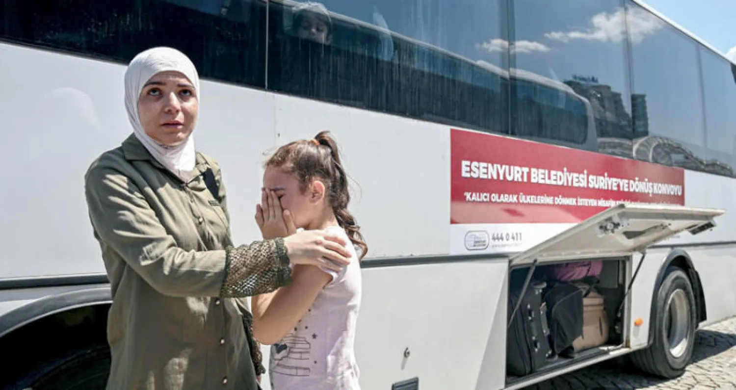 طفلة سورية مع والدتها تبكي أمام حافلة في إسطنبول ستقل مجموعة من السوريين إلى الحدود التركية ــ السورية (أ.ف.ب)