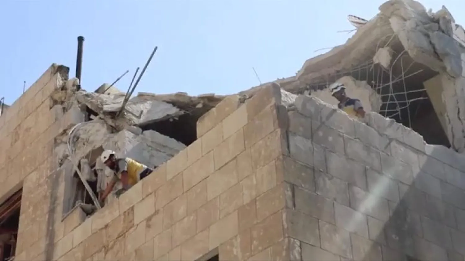 White Helmets stand on partially destroyed building after air strikes hit residential buildings in northwest Syria, in this picture grab taken from a video, July 12, 2019. White Helmets via REUTERS
