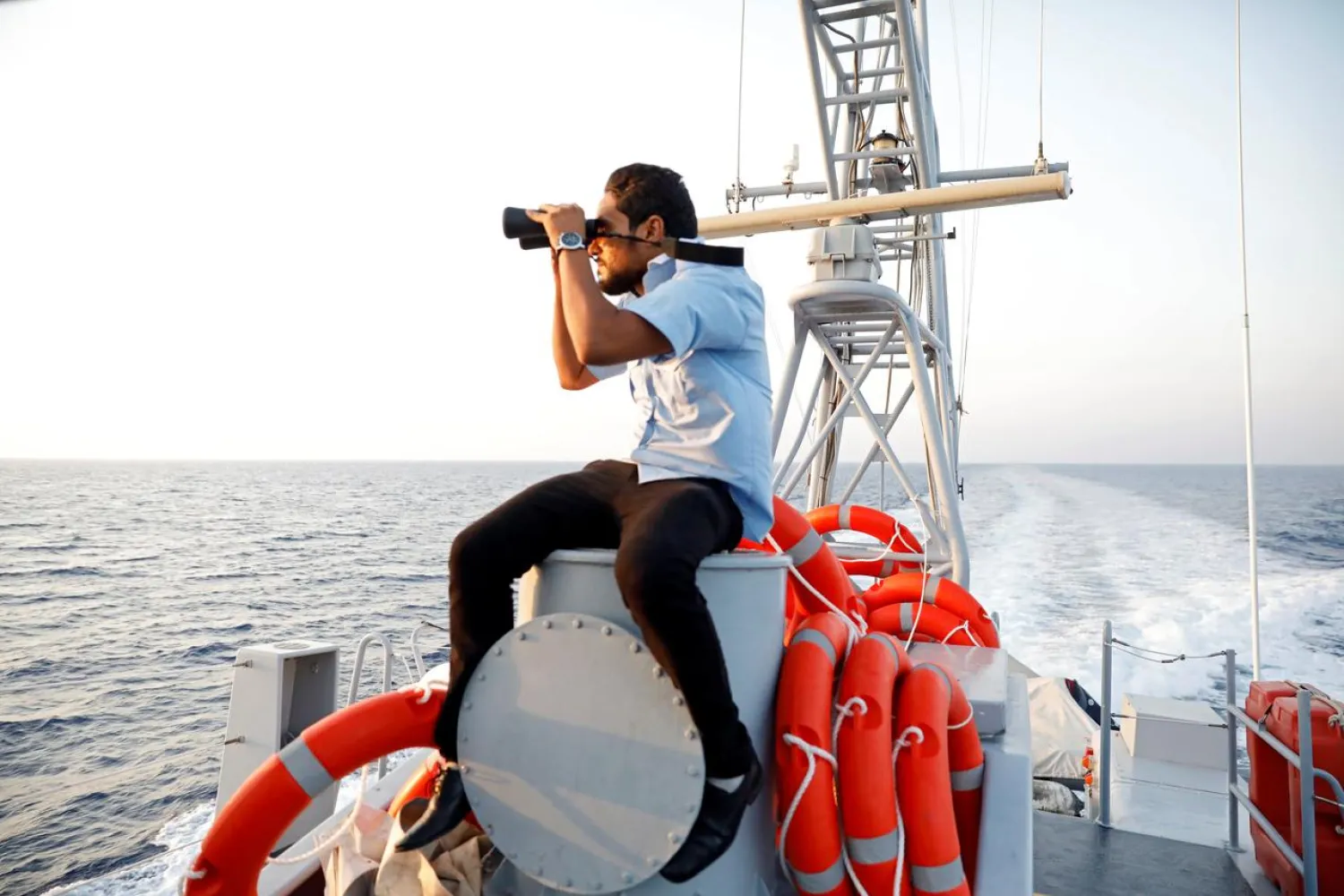 A member of the Libyan Coast Guard uses a pair of binoculars as he searches for migrants off the coast of Tripoli, Libya, August 9, 2017. (Reuters)