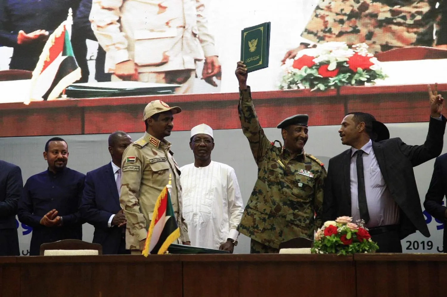Protest leader Ahmad Rabie (R), flashes the victory sign alongside General Abdel Fattah al-Burhan (2nd-R), TMC chief, during a ceremony to sign the landmark deal in Khartoum on August 17, 2019. (AFP)