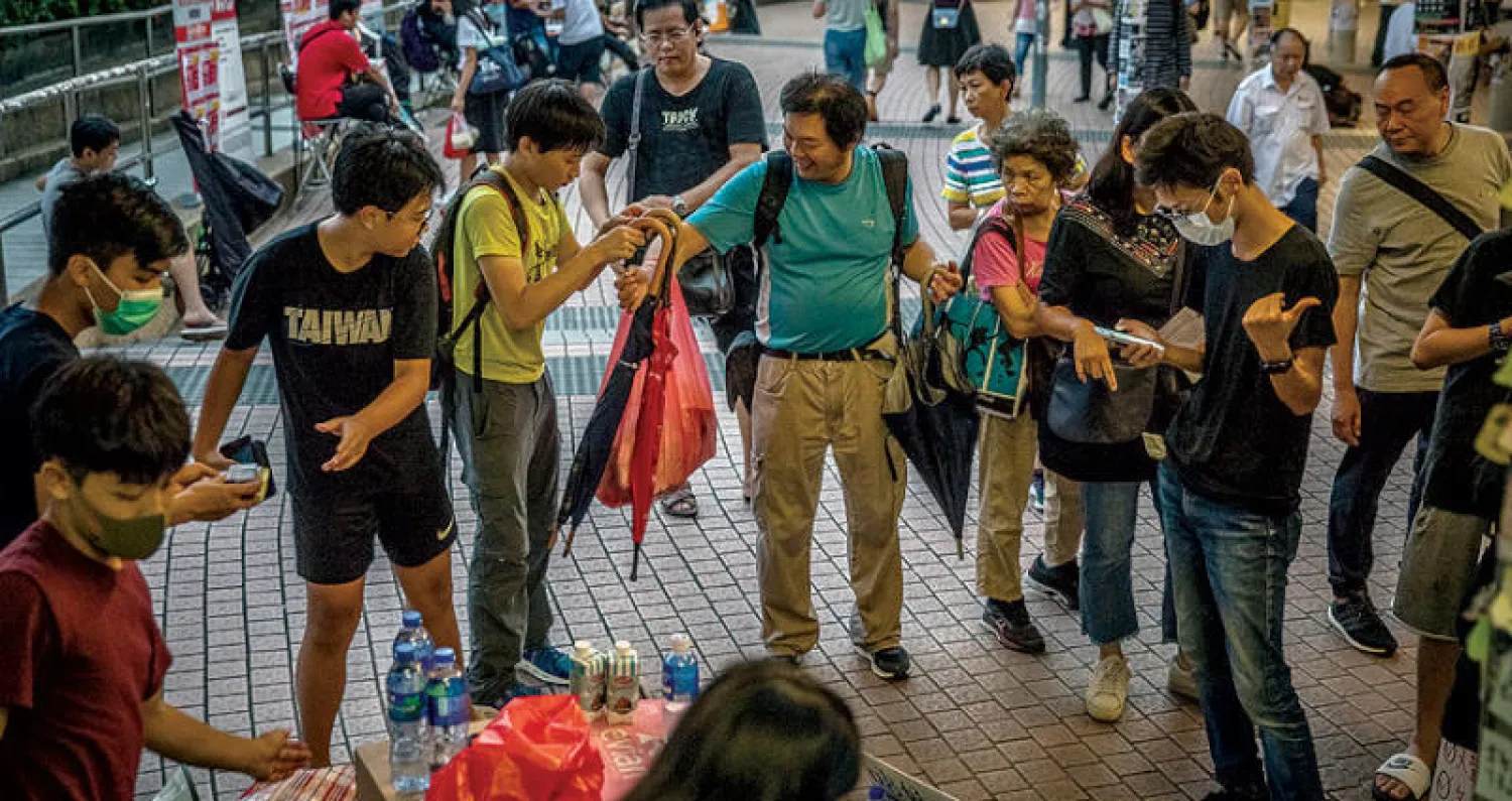 رجل يوزّع تبرعات على المتظاهرين في هونغ كونغ أمس (إ.ب.أ)