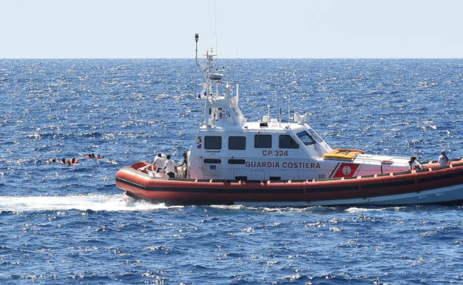 An Italian coast guard boat is seen next to migrants swimming after jumping off the Spanish rescue ship Open Arms, close to the Italian shore in Lampedusa, Italy August 20, 2019. REUTERS/Guglielmo Mangiapane
