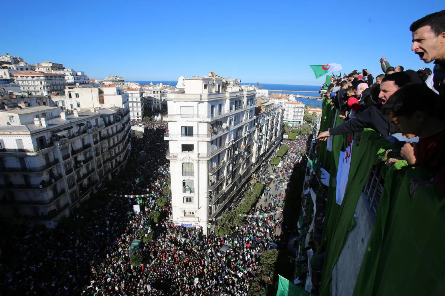 Demonstrators stand atop of a building during a protest in Algiers, Algeria March 15, 2019. (Reuters)