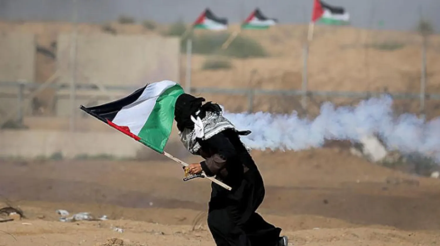 A woman raises a Palestinian flag during clashes with Israeli soldiers on the Gaza border with Israel on Friday, August 23, 2019 (Reuters)