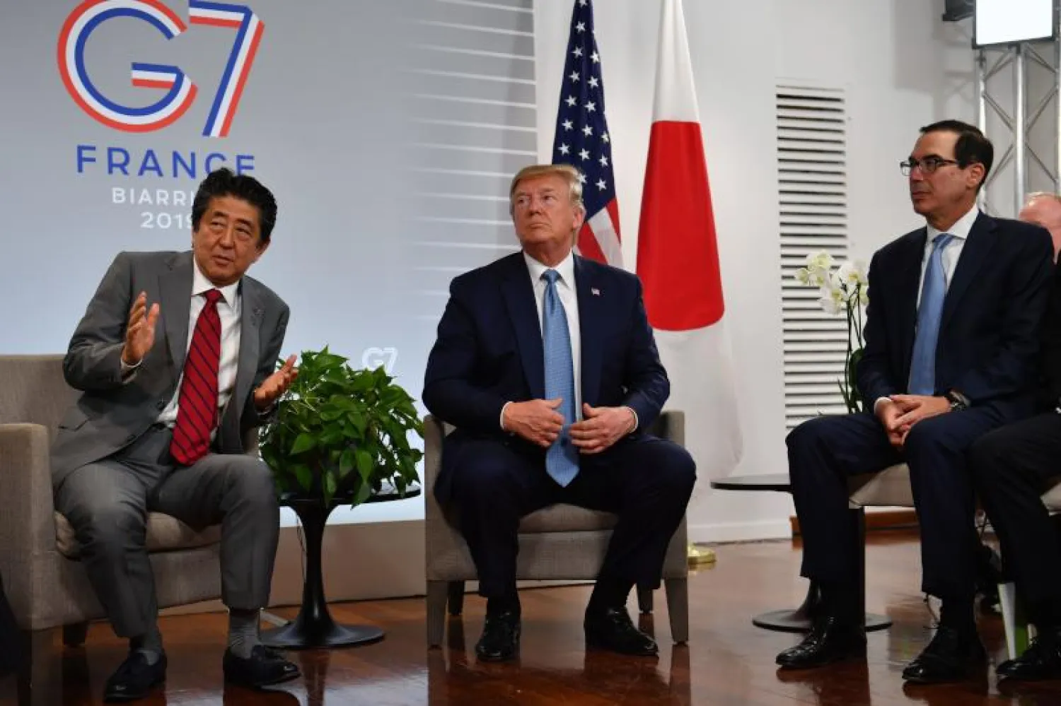 الرئيس الأميركي دونالد ترمب جالساً بجوار رئيس الوزراء الياباني شينزو آبي في قمة مجموعة السبع في فرنسا (أ.ف.ب)