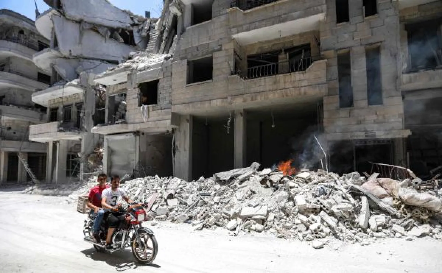 Men ride a motorcycle past debris outside a hospital damaged after a reported air strike in Jisr al-Shughur in the northeastern Syrian Idlib province on July 10, 2019. AFP
